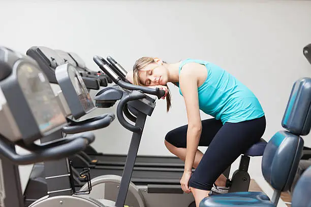 Young woman resting on the exercise machine.