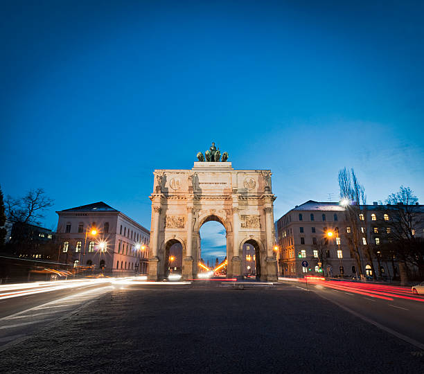 Victory Gate in Munich Dusk photograph of traffic passing the floodlit Victory Gate (Siegestor) in central Munich in Bavaria, Germany. The structure was completed in 1852. siegestor stock pictures, royalty-free photos & images