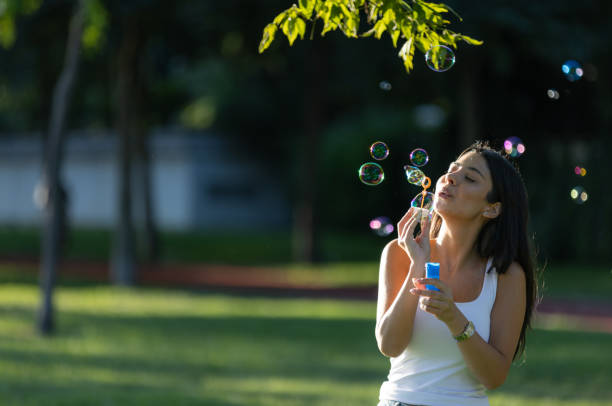 istock Pretty young woman is making soap bubbles on green field in summertime. 1552845656