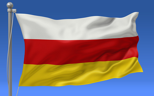 South Ossetia flag waving on the flagpole on a sky background