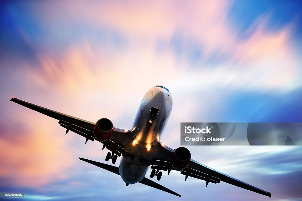 Airplane taking off against blue and pink sky Commercial airliner with landing lights on Commercial Airplane Stock Photo