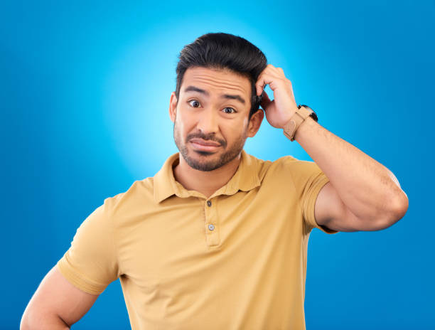 istock Portrait, head scratch and man confused over question, doubt or uncertain about problem crisis, error or decision. Studio, face and Asian male person unsure about choice isolated on blue background 1552848950