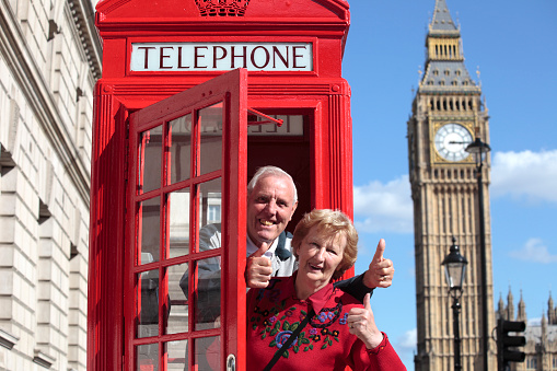 Senior couple in London with traditional telephone box. Big Ben in the background.
