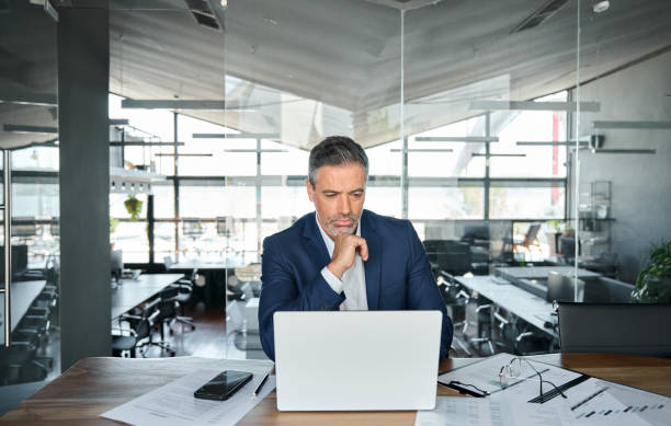 istock Busy serious business man ceo looking at laptop thinking in modern office. 1552851637