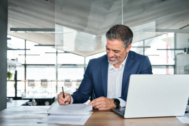 istock Happy mid aged professional business man signing documents in office. 1552851639
