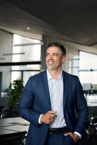 istock Happy mid aged business man ceo standing in office enjoying success, vertical. 1552851643