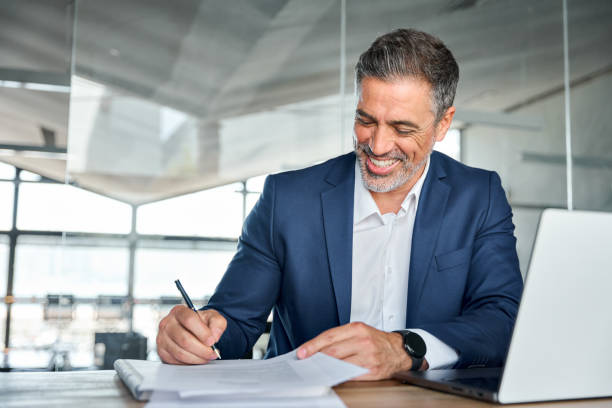 istock Happy satisfied middle aged professional business man signing documents. 1552851650
