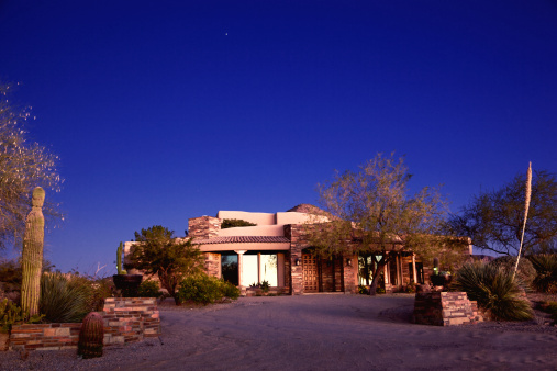 Luxury North Phoenix and Scottsdale, AZ modern stone and adobe home  in a desert landscape setting on a clear sky at twilight, clear blue night sky