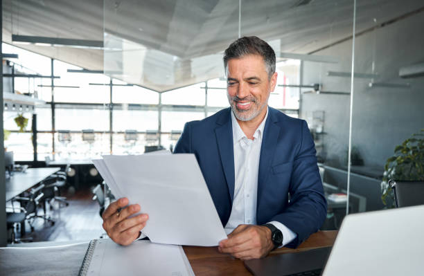 istock Middle aged professional business man ceo manager checking documents in office. 1552852181