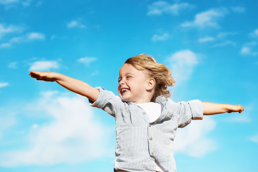 A happy child playing in a summer park. The girl is running, spinning, spinning and laughing. Entertainment during the summer holidays.