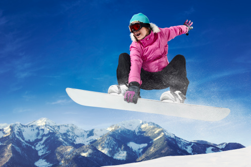 Girl in pink and black clothes snowboarding.