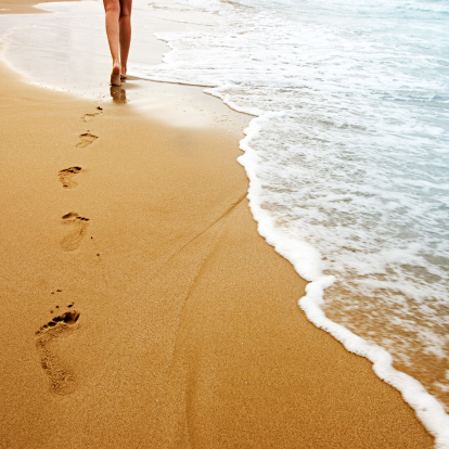 A young woman walking on the sand.