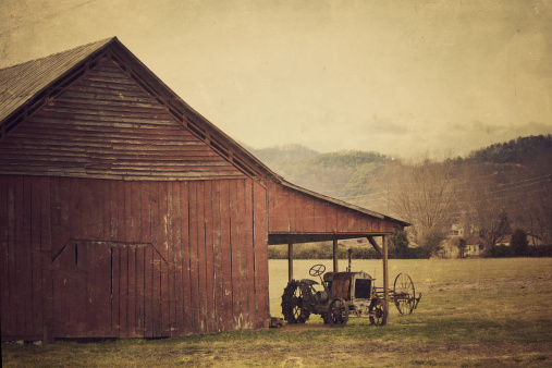 american rural scene - old barnyard and rusty tractor under its roof, tennessee- usa