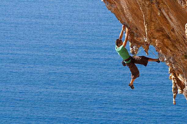 istock A man rock climbing on a large steep cliff near the ocean 155285833