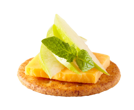 Cheddar and apple slices on a cracker with a mint garnish.  Isolated on white background, larger files come with clipping path.  Professionally shot, color corrected, exported 16 bit depth, retouched and saved for maximum image quality.