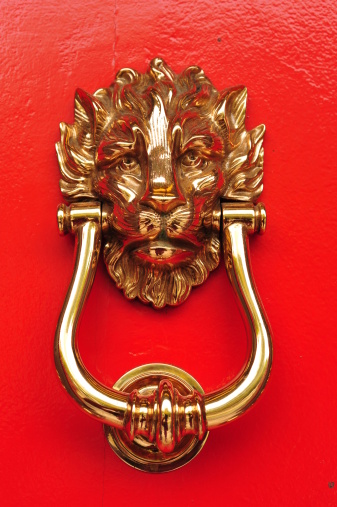 Head of a lion in silver color for knocking on a white door, isolated on a white background. Knocker in the form of a muzzle of a lion with a ring, close-up