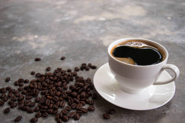 istock Black coffee in a white glass placed on an old cement table with coffee beans. 1552871642