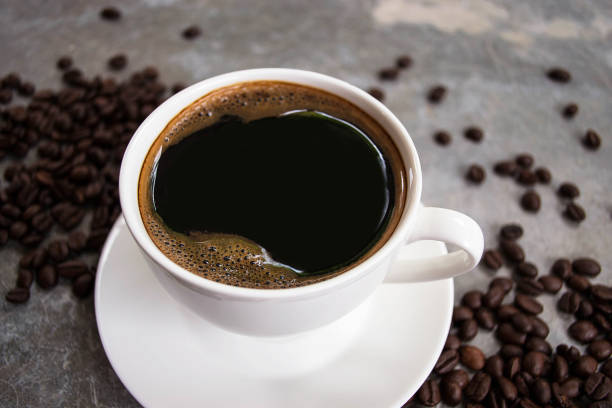 istock Black coffee in a white glass placed on an old cement table with coffee beans. 1552872153