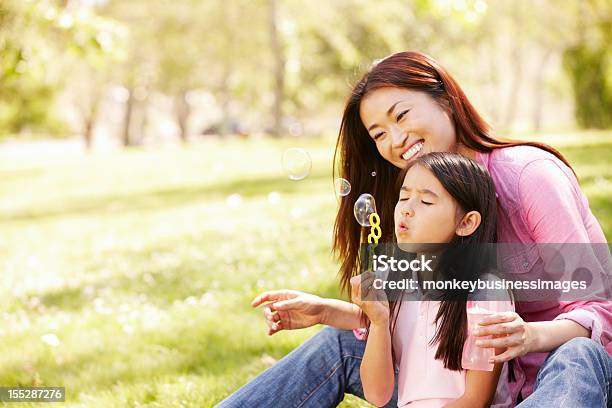 Asiático Soplando Burbujas Madre E Hija En El Parque Foto de stock y más banco de imágenes de Familia