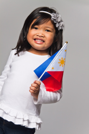 Cute three year old Filipino girl holding the Philippine flag.