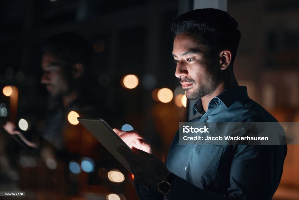 Night, work or man reading on tablet for research, project or planning a proposal in office building, startup or professional employee. Overtime, working or search on internet or online communication Business Stock Photo
