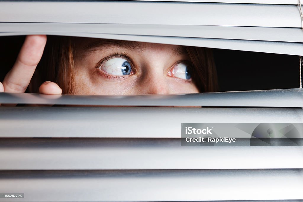 Jovem mulher s'assustar com algo visto através de cortinas de Veneza - Foto de stock de Medo royalty-free