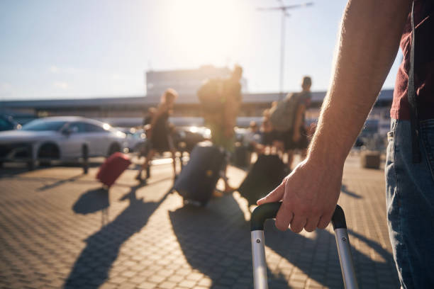 Group of people walking to airport terminal Group of people walking to airport terminal at summer sunset. Selective focus on hand of man with suitcase. airport stock pictures, royalty-free photos & images