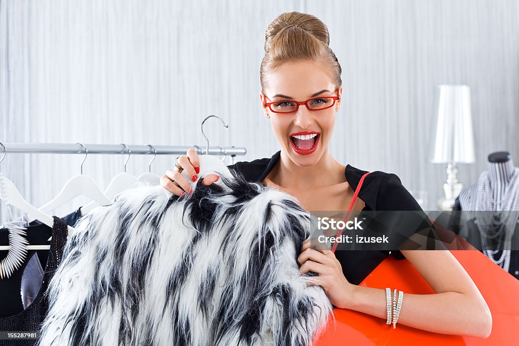 Happy woman during shopping Happy young adult woman shopping in luxury boutique, reacting on special price of fur jacket.  20-24 Years Stock Photo