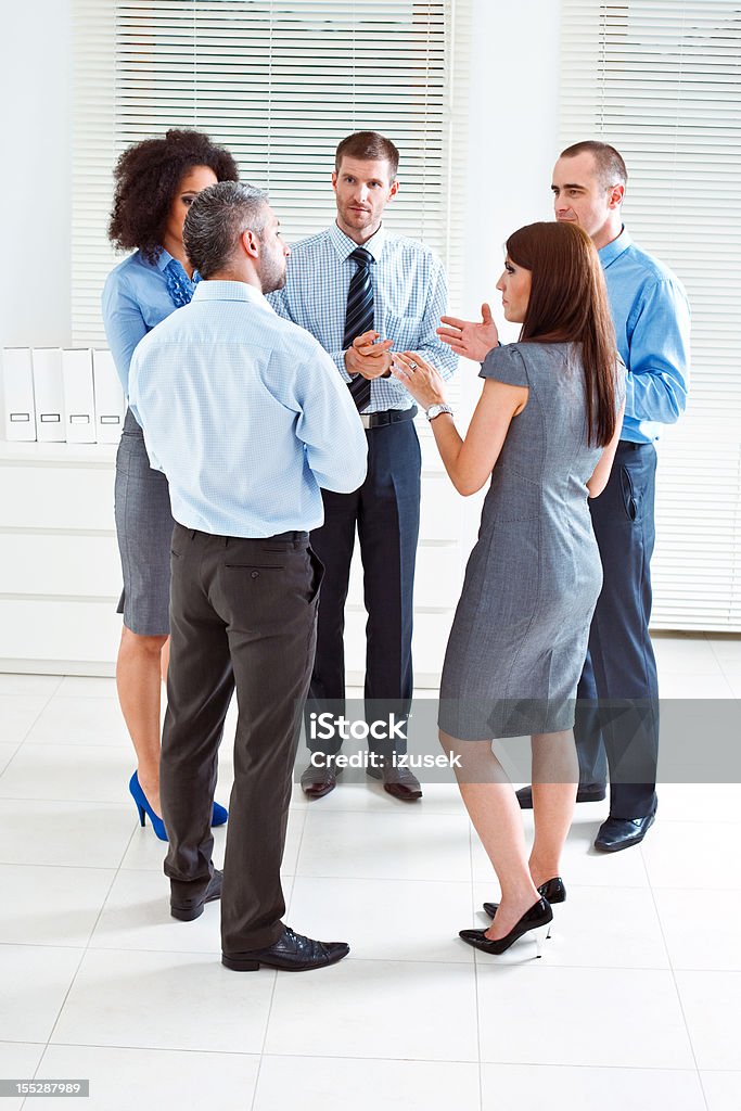 Planning Five serious business people standing in an office and having conversation. 25-29 Years Stock Photo