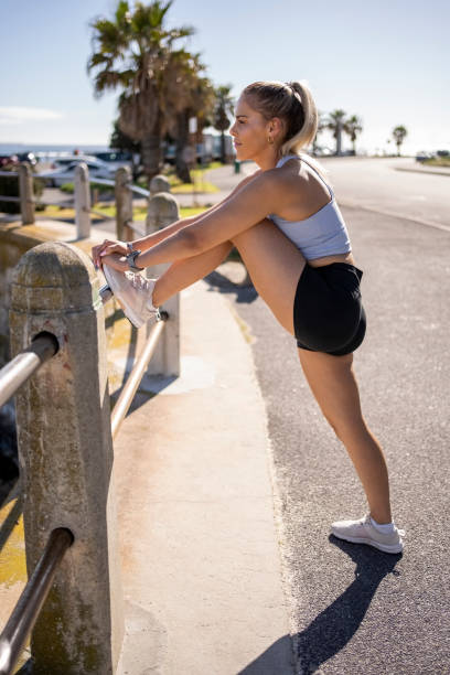 朝のランニングの前に足を伸ばす健康な若い女性 - railing beautiful human leg people ストックフォトと画像