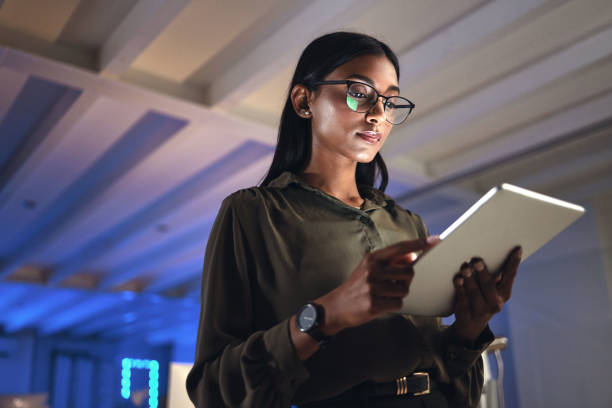 tableta, diseñadora y mujer seria investigan en la oficina de inicio de negocios por la noche en la fecha límite. tecnología, profesional creativo o empresario indio leyendo información, correo electrónico o aplicación en neón empresa - drawing women expertise business fotografías e imágenes de stock