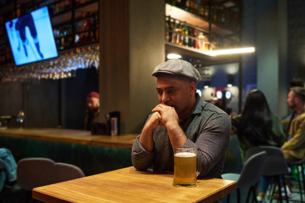 молодой депрессивный мужчина в повседневной одежде держит руки у лица - hard liquor color image photography brewery стоковые фото и изображения