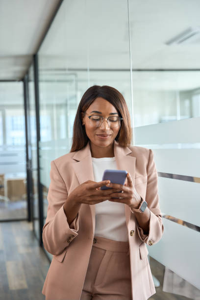 istock Young happy professional business woman using mobile phone in office, vertical. 1552918825