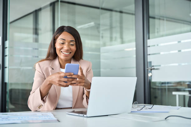istock Happy professional business woman using cell phone in modern office. 1552918836