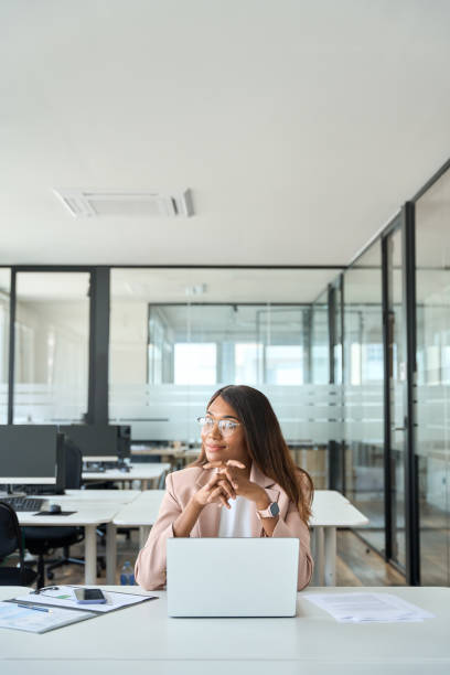 istock Professional businesswoman working on computer in office looking away, vertical. 1552919194