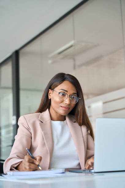 istock Business woman manager working in office looking at laptop writing, vertical. 1552919385