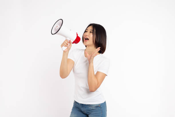 istock Asian woman smiling face holding megaphone shouting posing isolated on white background, 1552968454