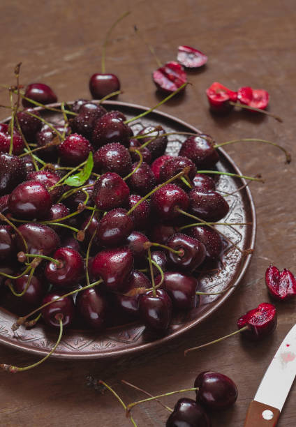 istock Sweet red cherry in a flat plate on a wooden table. 1552975881