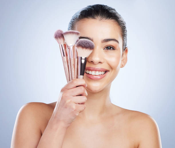istock Makeup brush, portrait and happy asian woman studio with cosmetics, tools or application on grey background. Face, smile and lady wellness model with beauty, glamour or contour cover results routine 1552984029