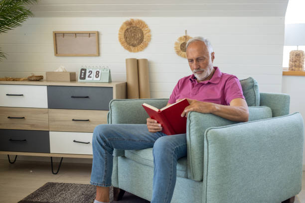 istock Senior man reading a book at home 1552988261