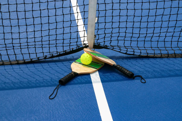 istock Pickleball paddles and ball by the net on a blue court 1552988832