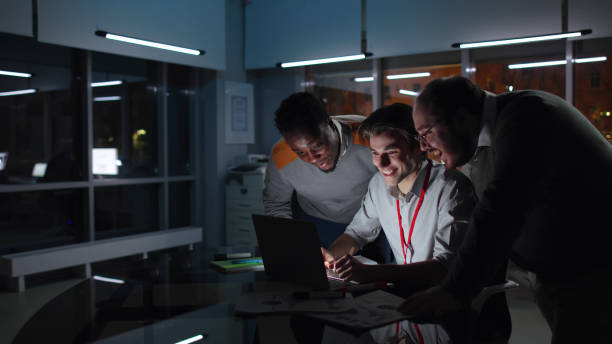 istock Multiethnic colleagues work on laptop and smile in dark office 1552995963