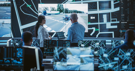 Diverse Team of Specialists Analyze Surveillance Feeds, Monitor Targets on a GPS City Map, Ensure Efficient Traffic Operations. Intensive Work in a Monitoring Room with Big Data Analytics Engineers