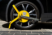 Car wheel blocked by a yellow metal lock or clamp.