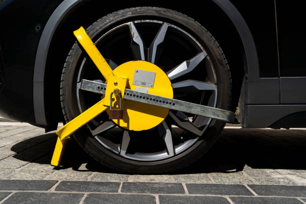 Car wheel blocked by a yellow metal lock or clamp. Car wheel blocked by a yellow metal lock or clamp. Vehicle illegal parking violation in a restricted zone. car boot stock pictures, royalty-free photos & images