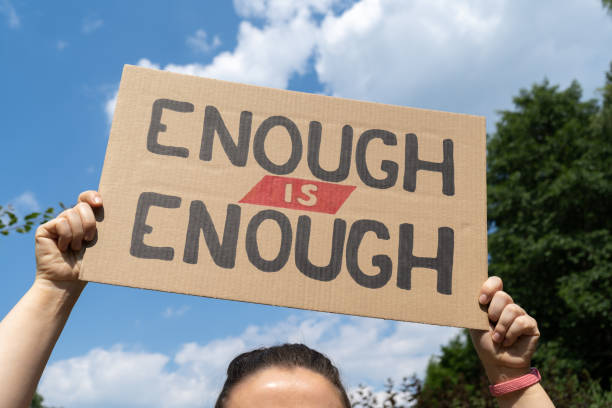 istock Hand holding placard sign with text Enough is enough at protest rally demonstration. 1553002830