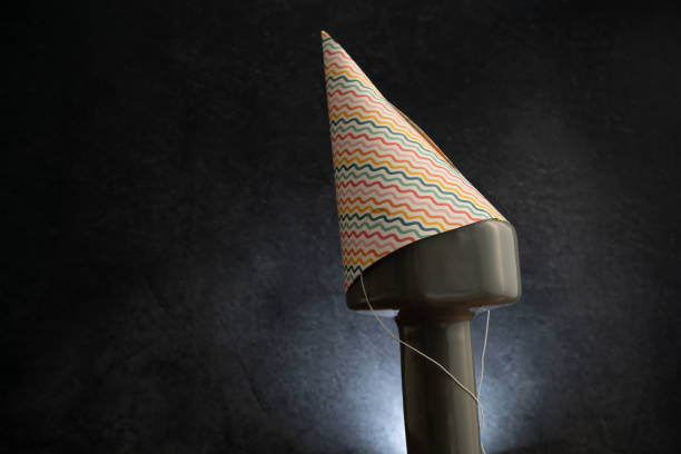 Heavy gym dumbbell in a colorful Birthday party hat. Exercise equipment as a gift idea. Healthy fitness lifestyle composition concept with copy space.