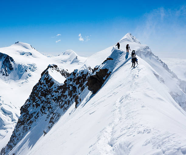 Climbers balancing in blizzard Climbers balancing in blizzard on a narrow ridge of Lyskamm (aka Maneater, 4480 m) mountain ridge stock pictures, royalty-free photos & images