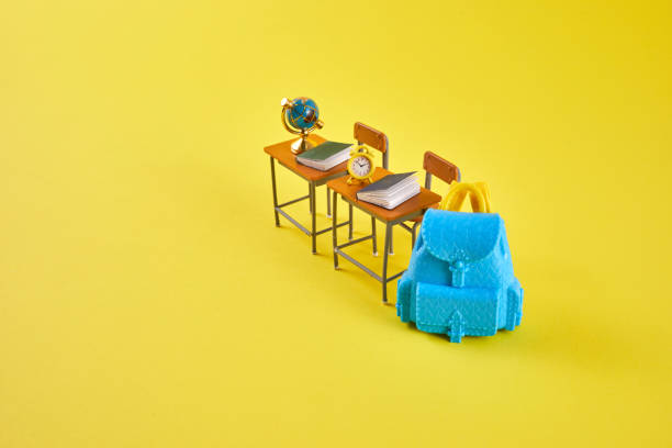 istock School desk with school accessory and blue backpack on yellow background 1553012665