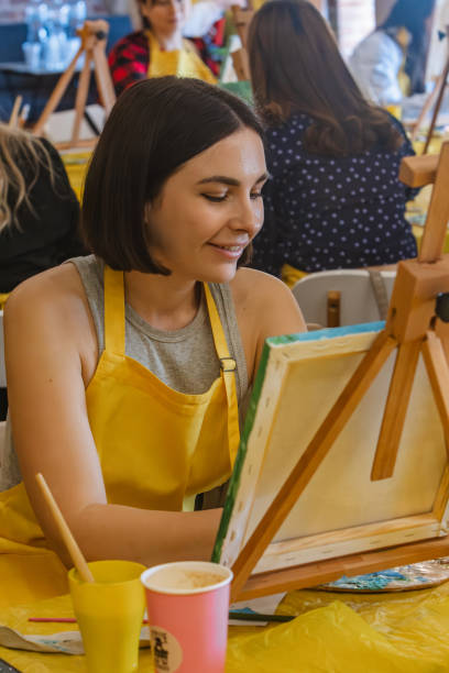 istock Woman with brush painting on canvas 1553043020